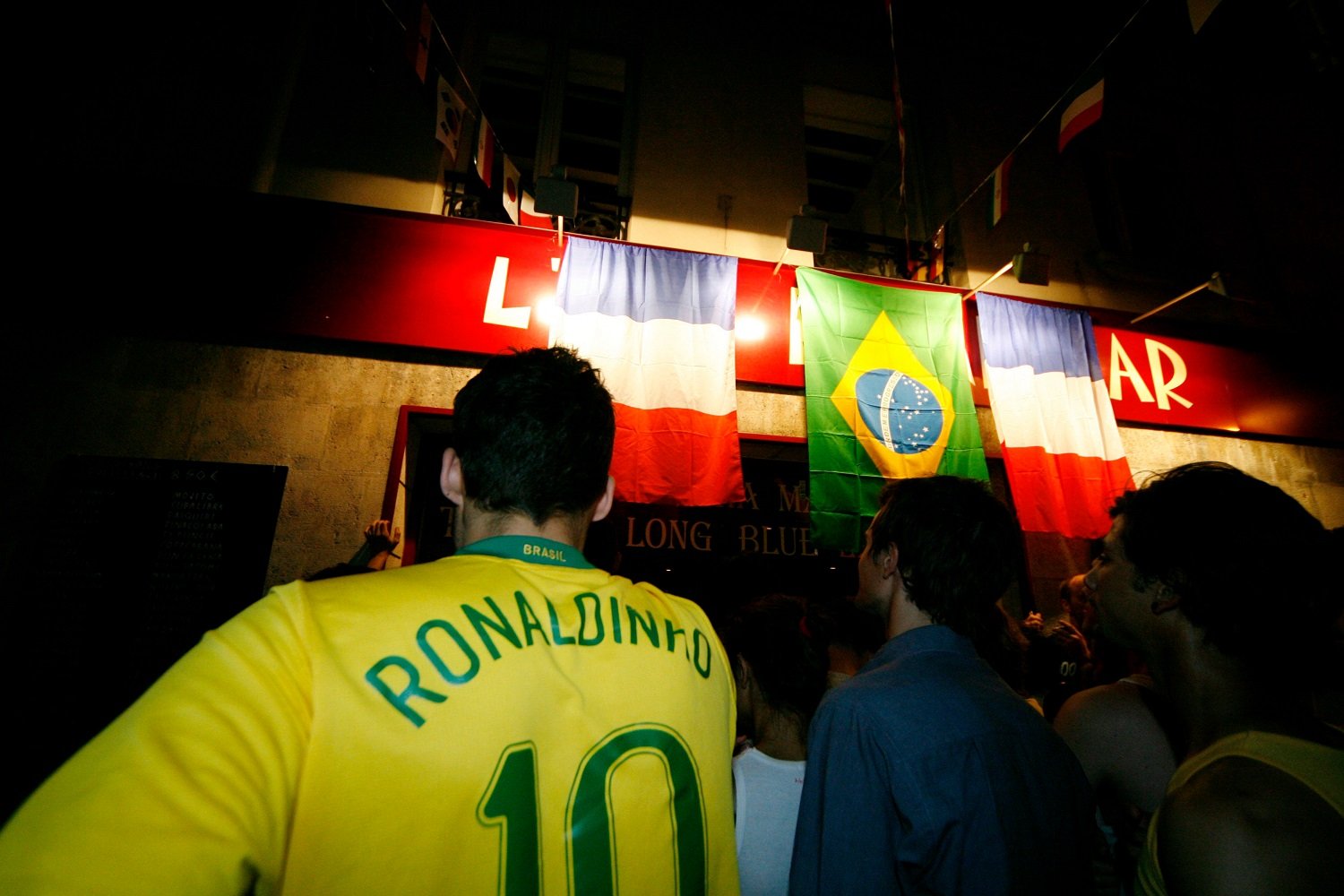 足球（球迷）聚集在一起观看巴西和法国之间的比赛。 其中一人穿着巴西国家队队服，队服上写着“罗纳尔迪尼奥”的名字，背后印着10号。